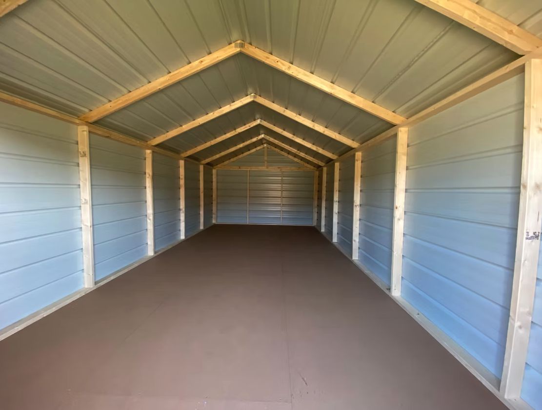 Interior of a long economy shed with metal walls, wood framing and floor